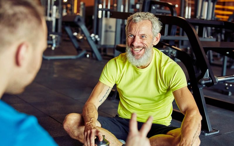happy-middle-aged-man-discussing-something-with-fitness-instructor-or-personal-trainer-and-smiling.jpg